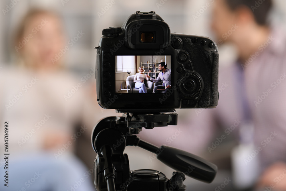 Male journalist with microphone having an interview with woman on camera screen in studio, closeup