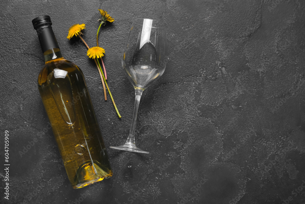 Bottle and glass of dandelion wine on black background