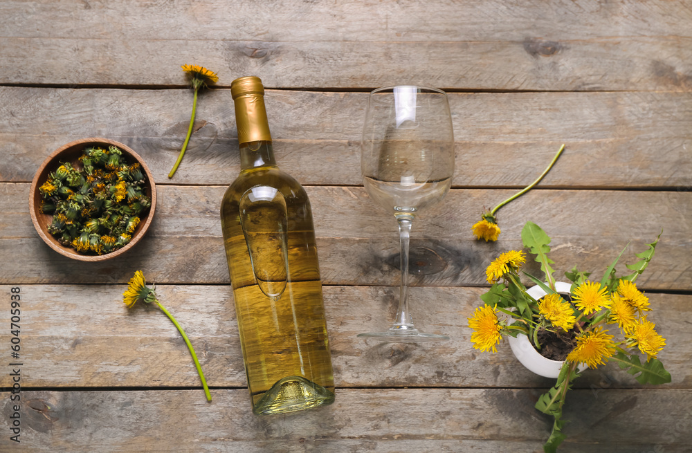 Bottle and glass of dandelion wine on wooden background