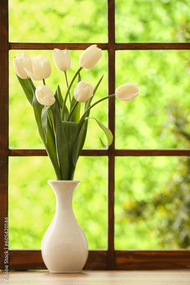 Vase with blooming tulip flowers on windowsill