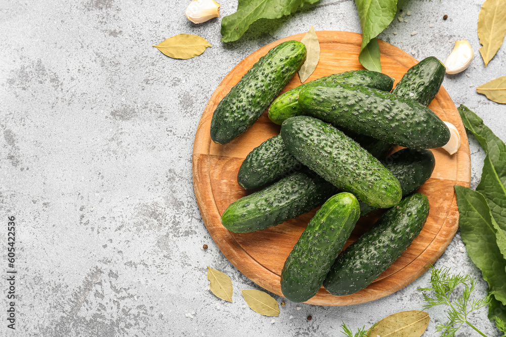 Wooden board with fresh cucumbers for preservation on light background