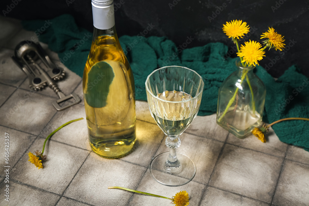 Bottle and glass of dandelion wine on grey tile table