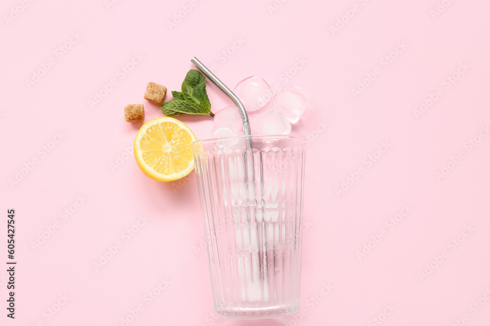 Glass with lemons, mint and ice cubes on pink background