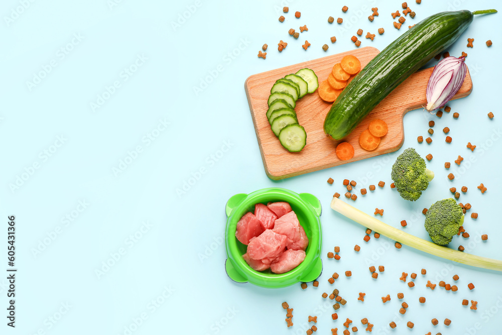 Composition with dry pet food, raw meat and natural products on blue background