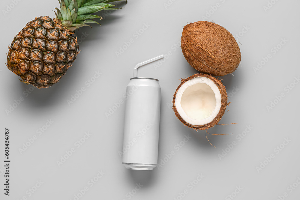 Composition with can of fresh soda, pineapple and coconut on grey background