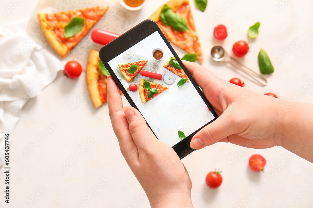 Woman taking photo of tasty pizza margarita on white background