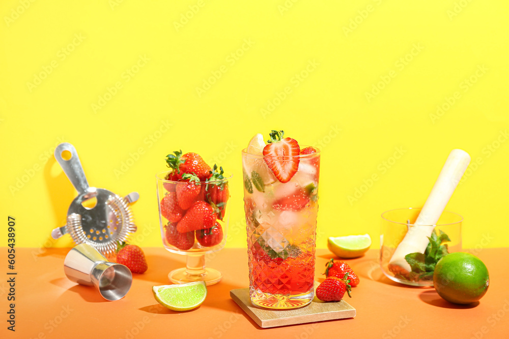 Glass of delicious strawberry mojito on color background