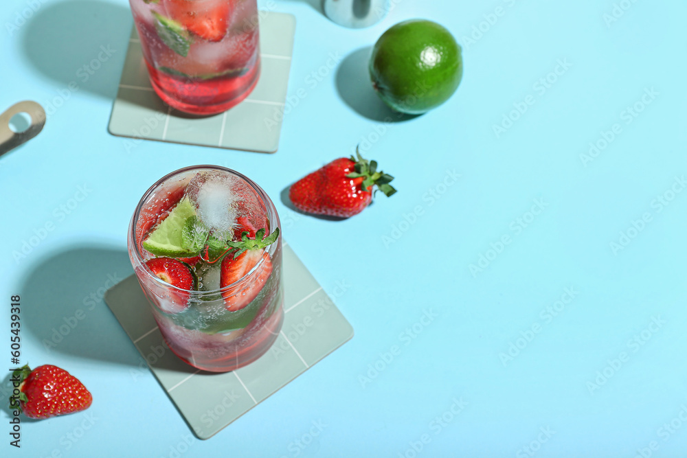 Glasses of delicious strawberry mojito on blue background