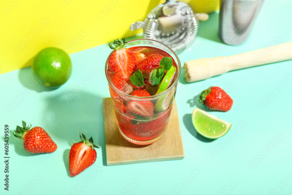 Glass of delicious strawberry mojito on color background