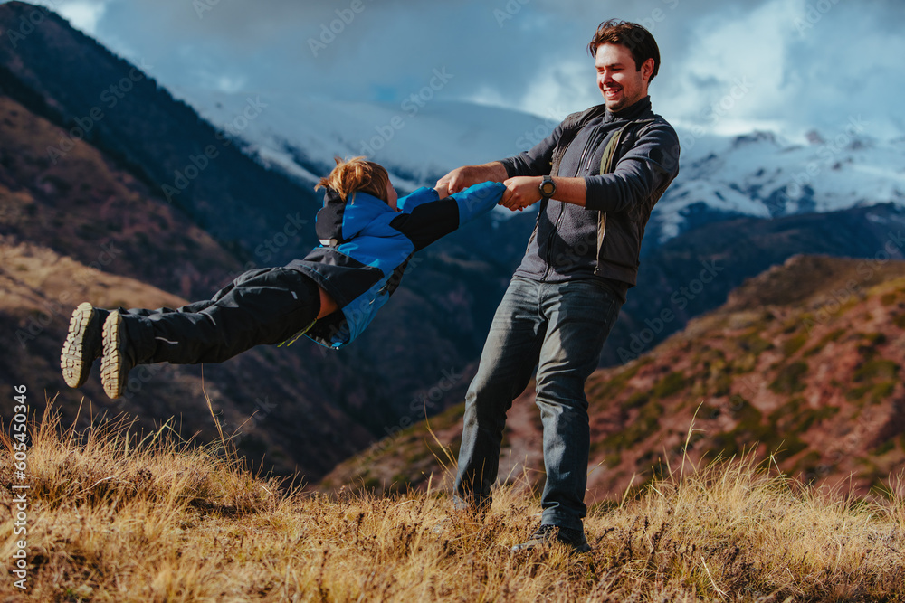 Happy young man having fun with his son in the mountains