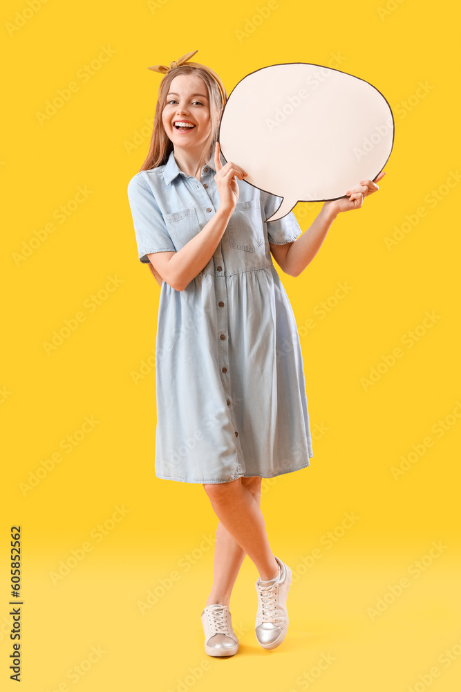 Happy young woman with blank speech bubble on yellow background