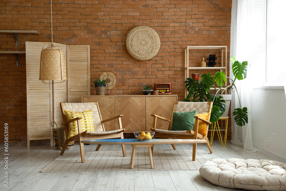 Cozy wooden armchairs with cushions and fruit basket on surfing board in interior of living room