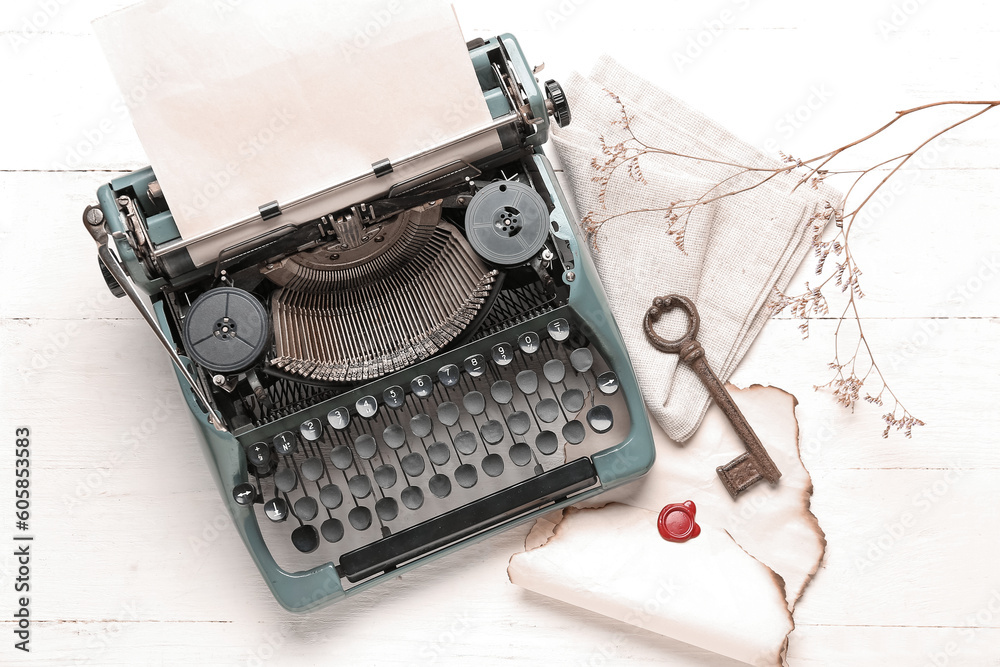 Composition with vintage typewriter, key, old parchment and blooming tree branch on white wooden tab