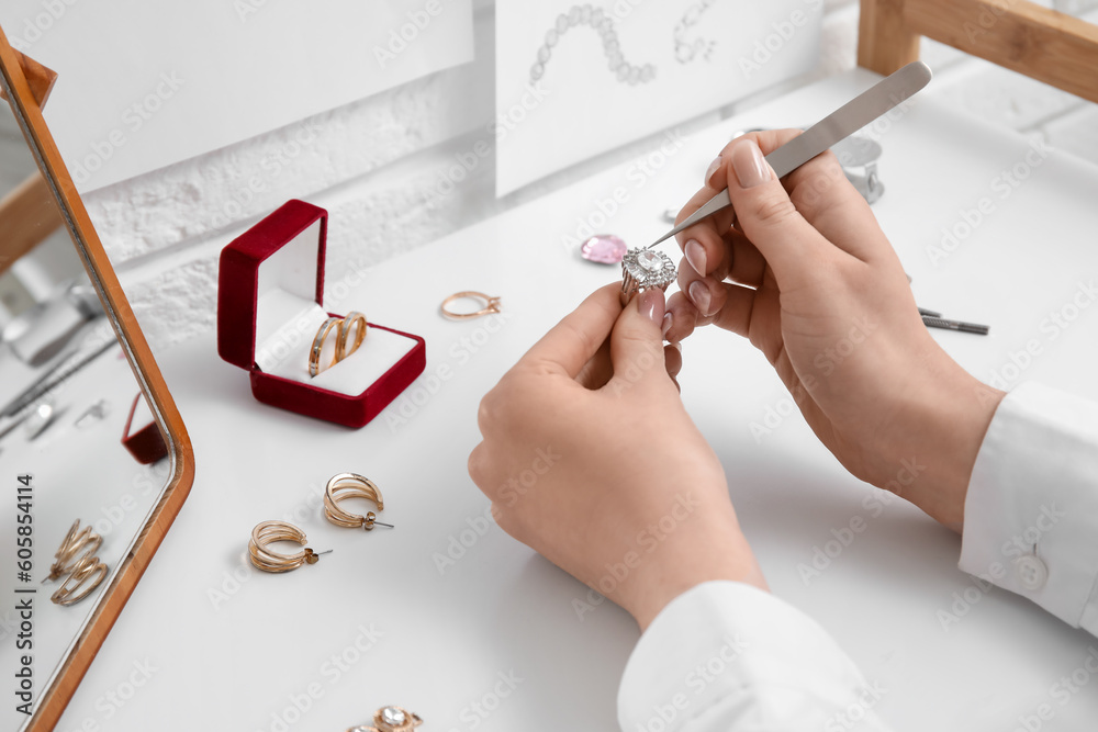 Female jeweler making ring on white table, closeup