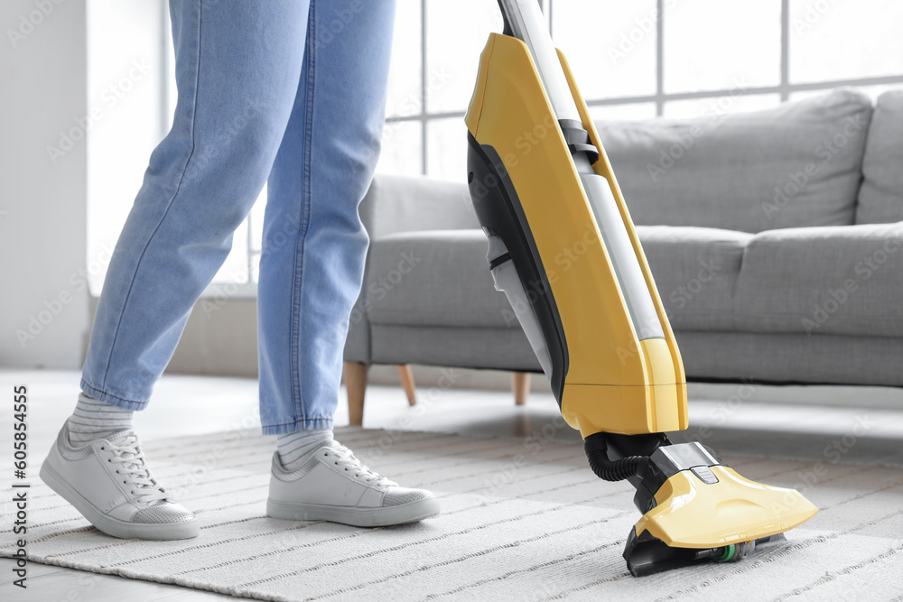 Young woman hoovering carpet at home, closeup