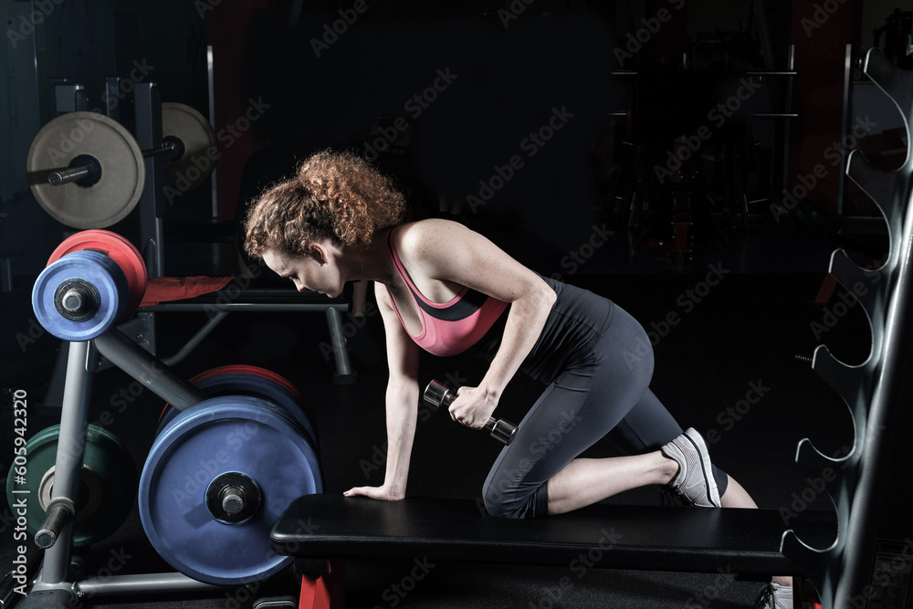 attractive young woman engaged with dumbbells in the gym.