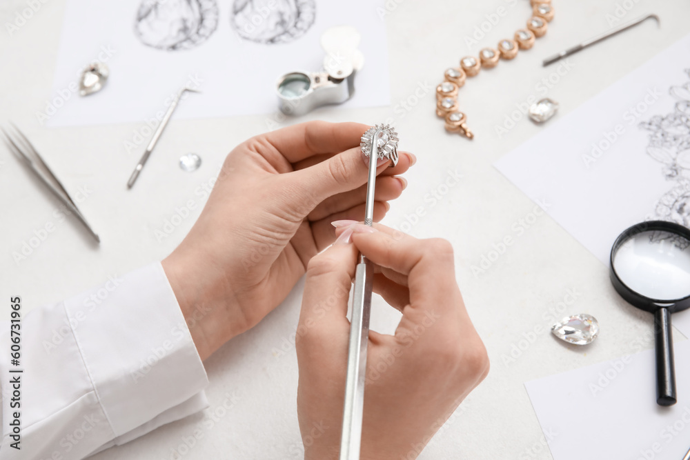 Female jeweler making ring on white table, closeup