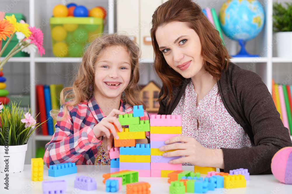 Cute little girl and her mother playing colorful plastic blocks