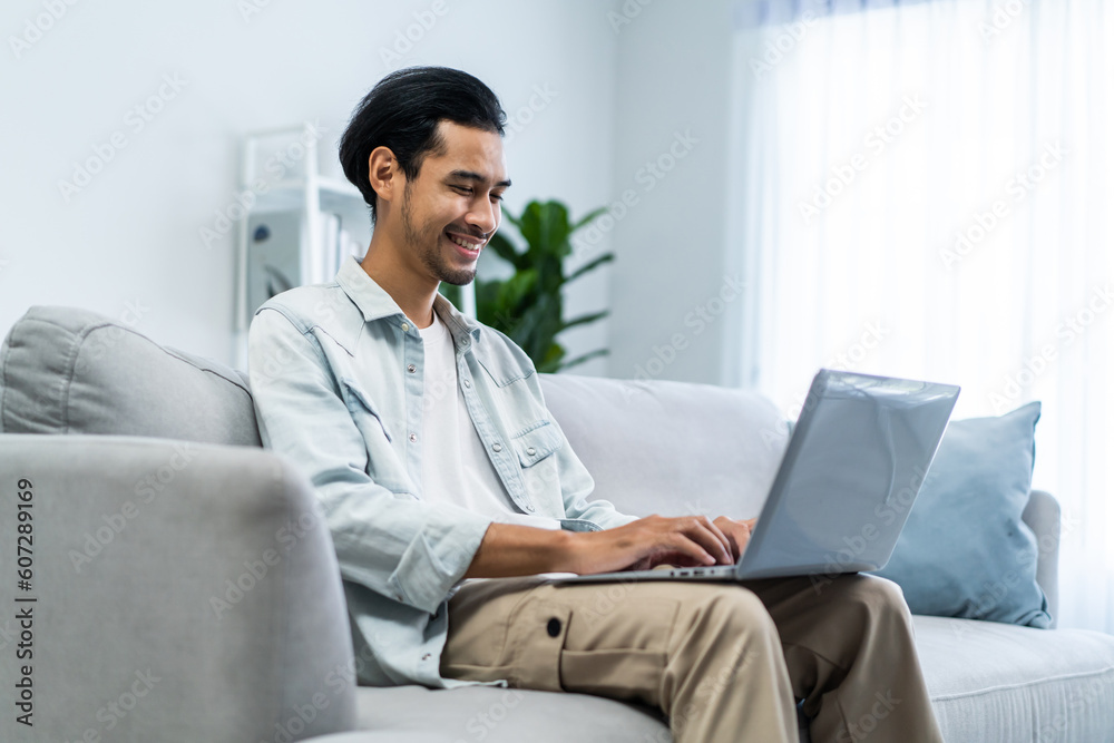 Asian young handsome businessman typing on computer alone in house.