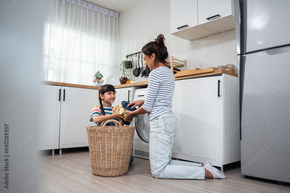 Caucasian beautiful mother teaching young daughter wash dirty clothes. 