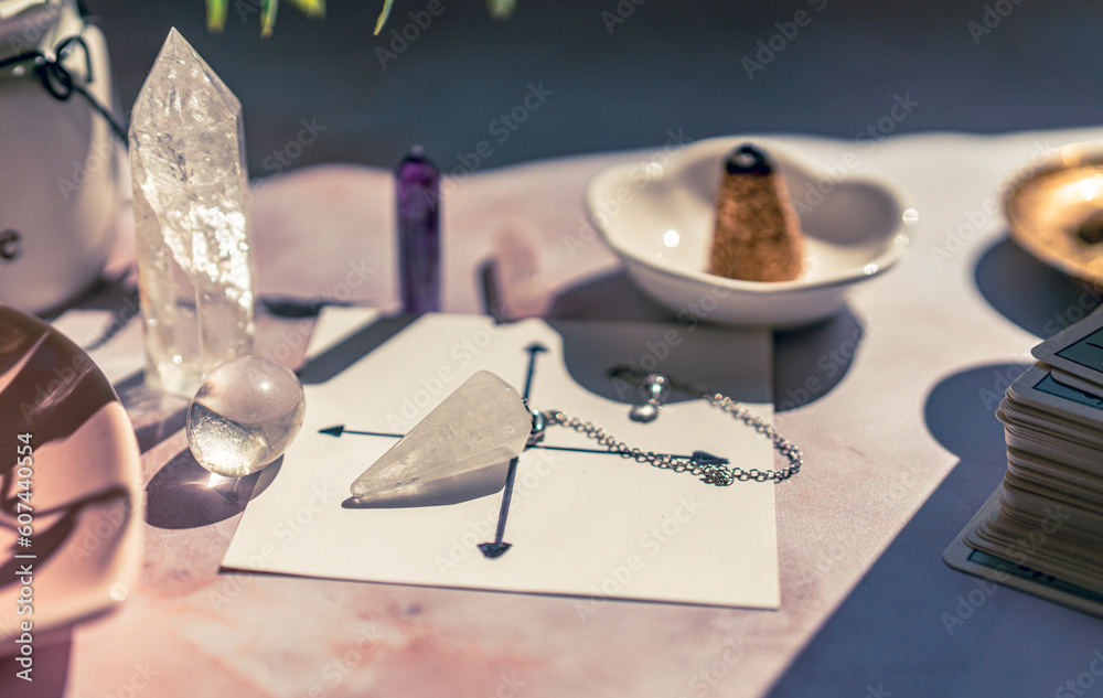 Gemstones for esoteric spiritual practice. Rock crystal pendulum on the table. Divination with a pen