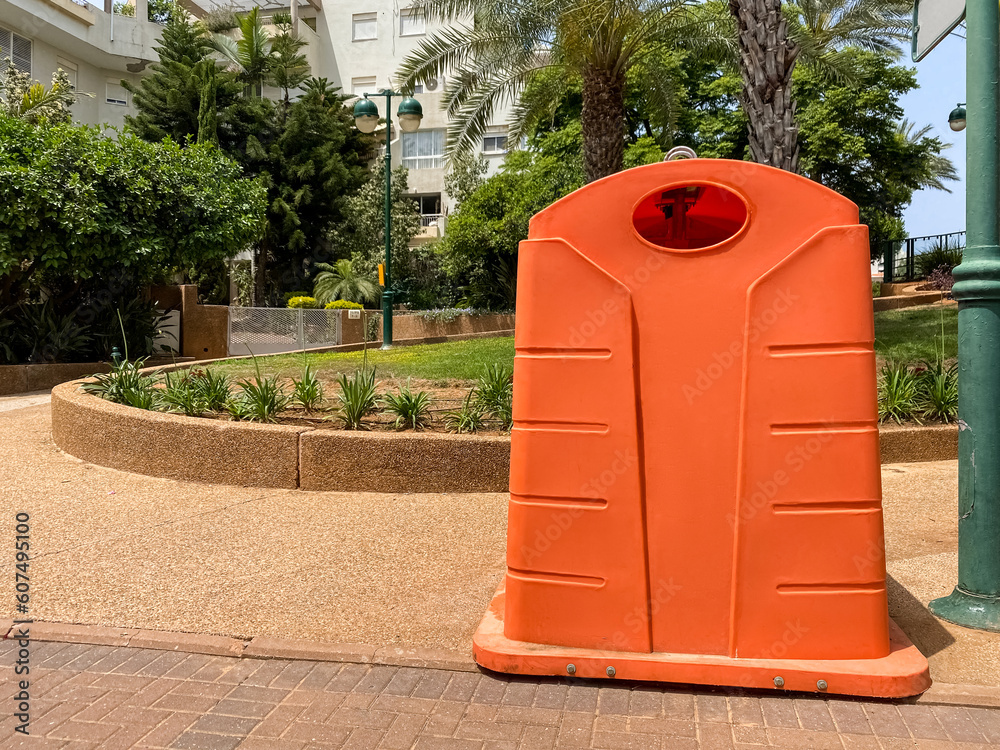 Orange garbage container on city street