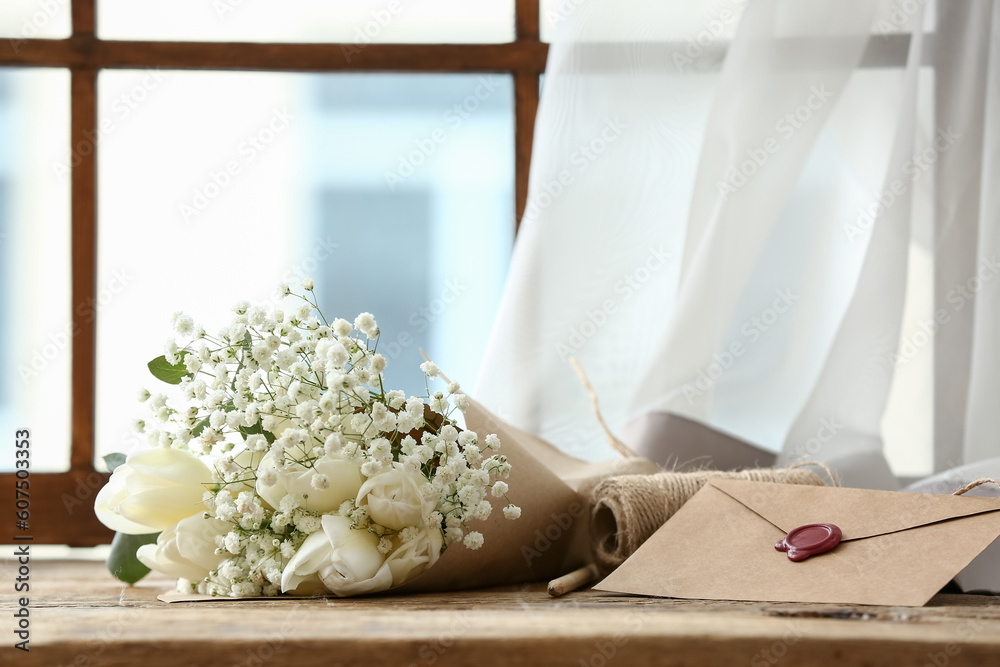 Bouquet of blooming tulip flowers and envelope with wax seal on windowsill