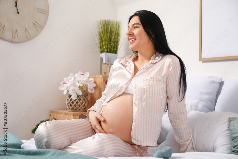 Young pregnant woman sitting in bedroom