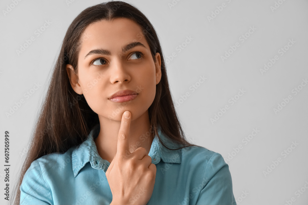 Thoughtful young woman on light background, closeup