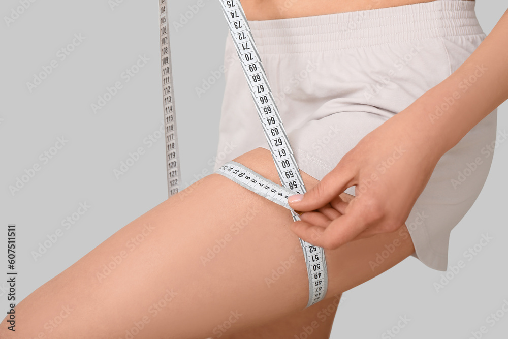 Young woman with measuring tape on white background, closeup. Diet concept