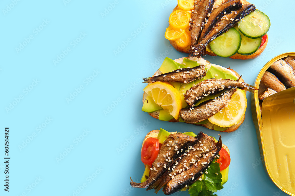 Tasty sandwiches with canned smoked sprats on blue background