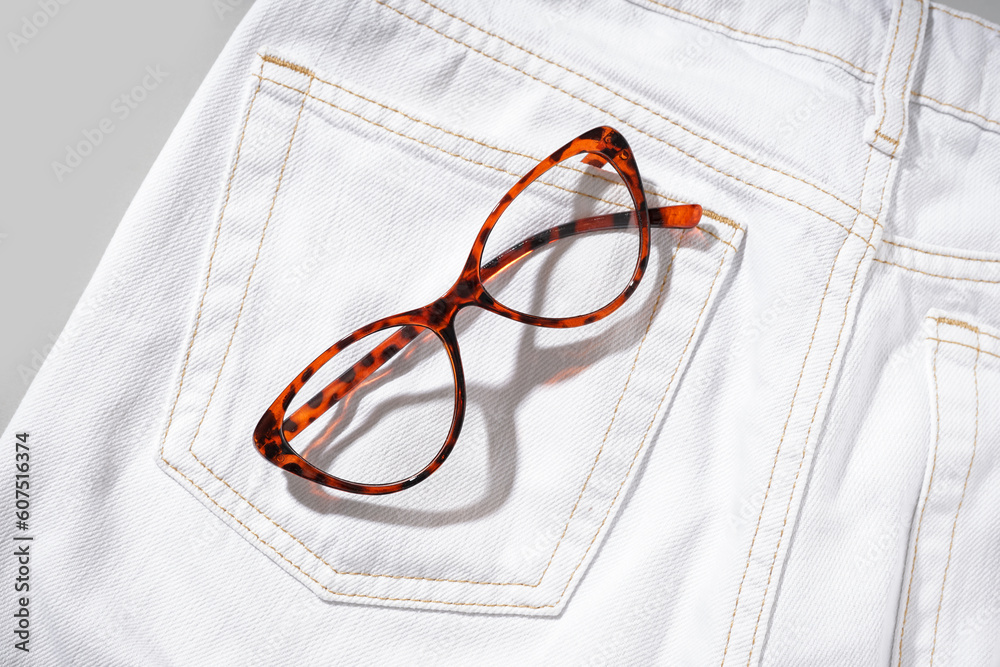 Stylish white jeans with leopard printed eyeglasses on grey background