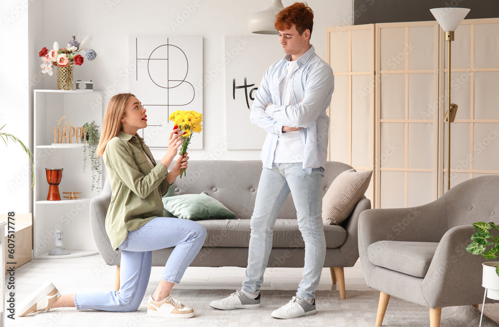 Young woman proposing to her thoughtful boyfriend at home