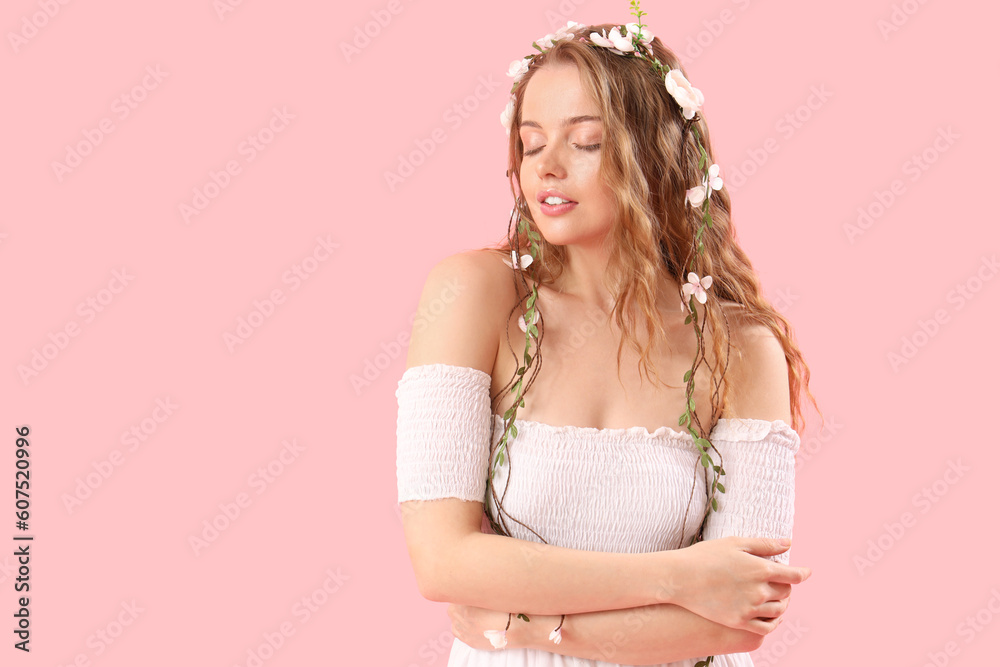 Beautiful young woman with flowers in her hair on pink background. Summer solstice