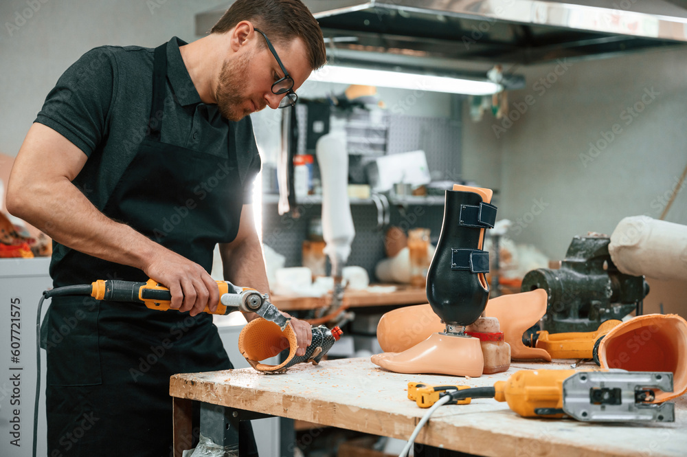 With drill. Technician working with prosthesis in modern laboratory