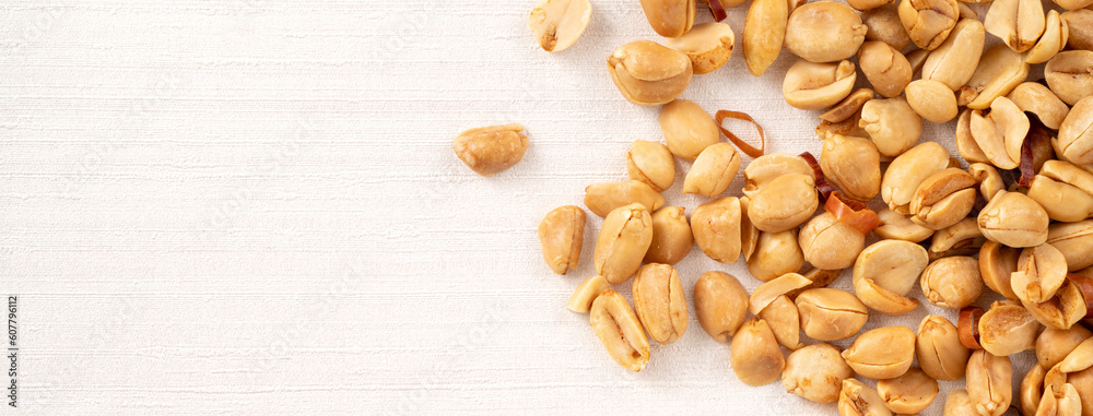 Spicy flavored peanut kernel spilling on white table background.