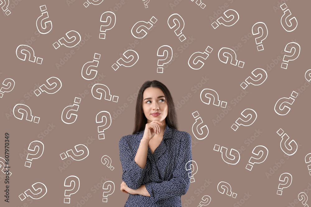 Thoughtful young woman with drawn question marks on brown background