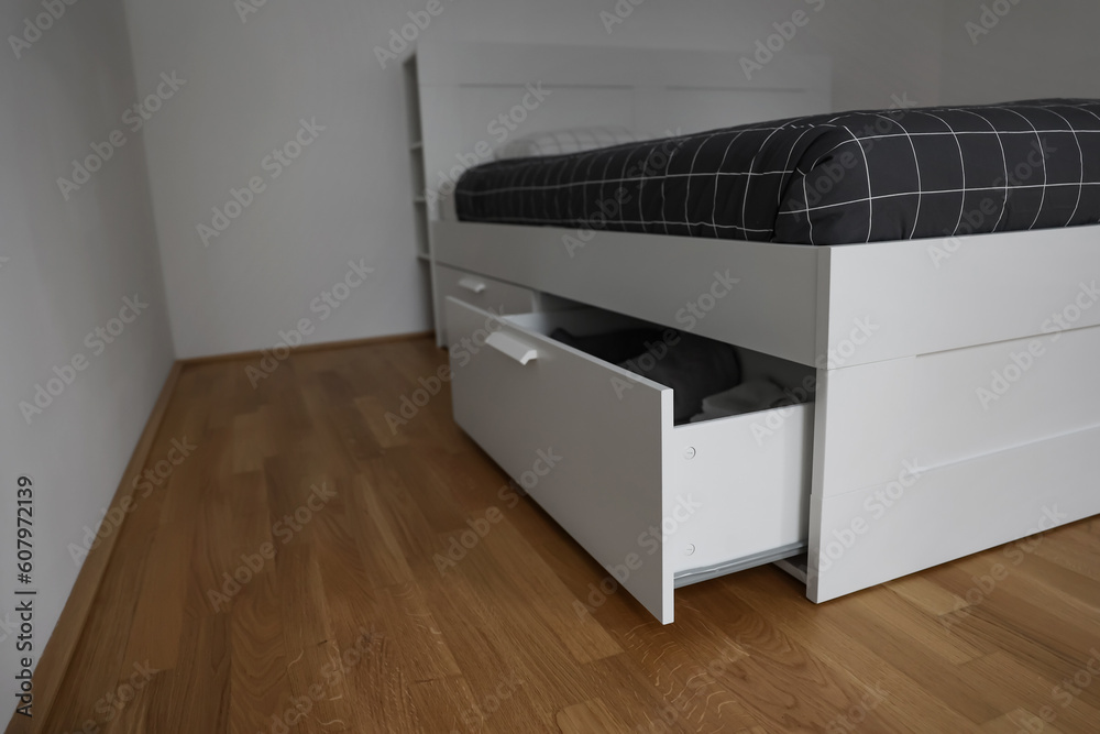 Modern bed with open drawer in room