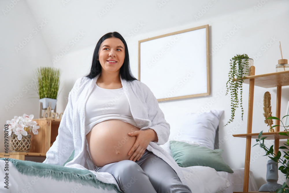 Young pregnant woman sitting in bedroom