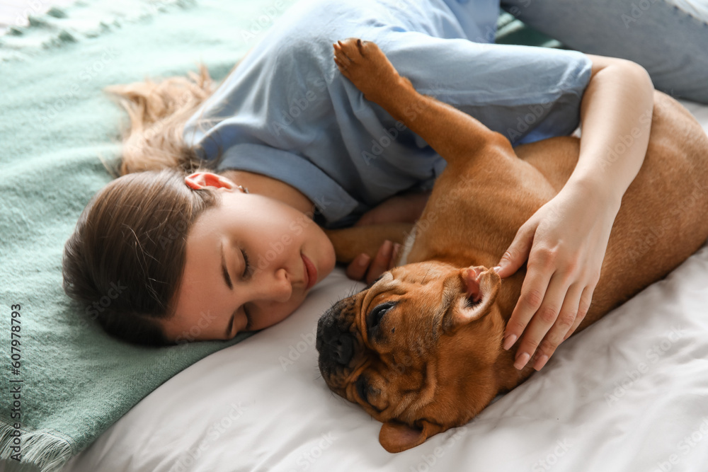 Young woman with cute French bulldog lying in bedroom, closeup