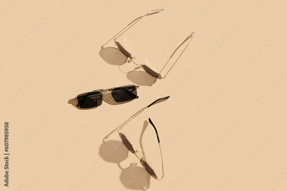 Different stylish sunglasses on beige background