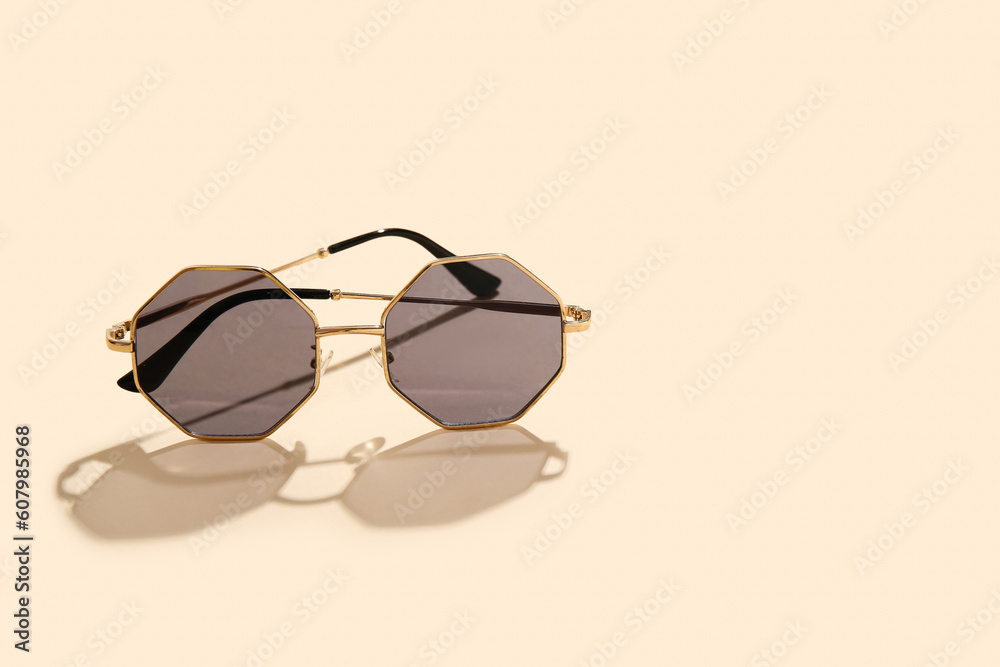 Stylish sunglasses on beige background