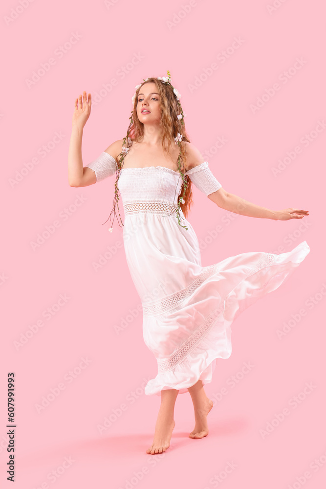 Beautiful young woman with flowers in her hair on pink background. Summer solstice