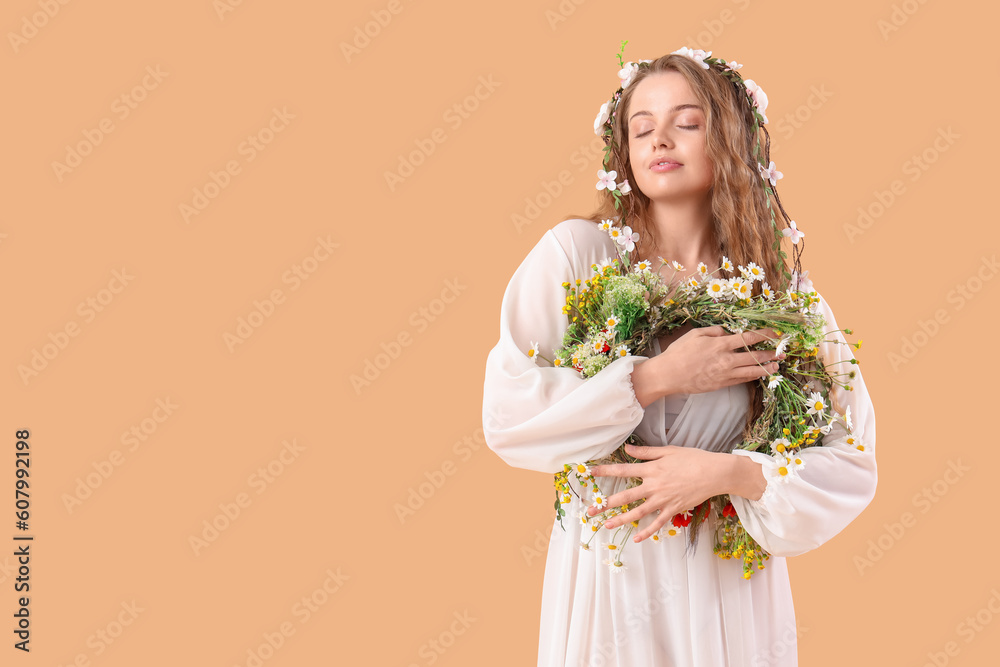 Beautiful young woman with flower wreath on beige background. Summer solstice