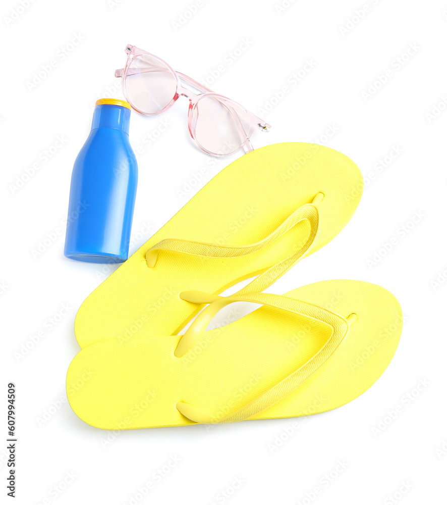 Bottle of sunscreen cream with sunglasses and flip flops isolated on white background