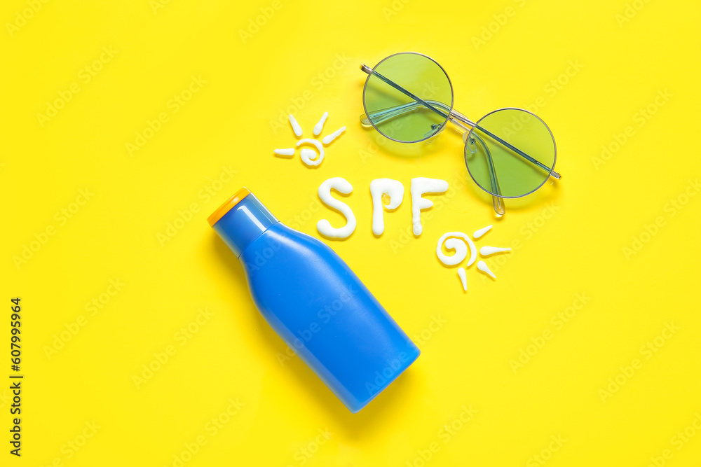 Composition with drawings made of sunscreen cream and sunglasses on yellow background