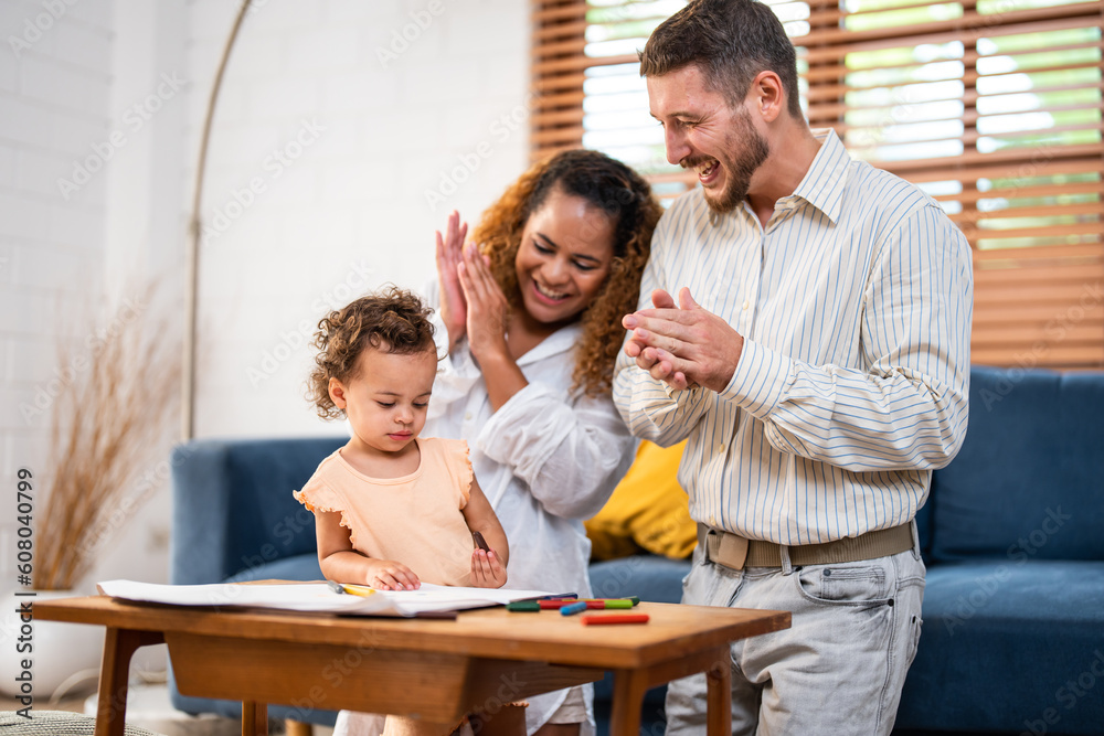 Caucasian family painting on paper with daughter indoors in house. 