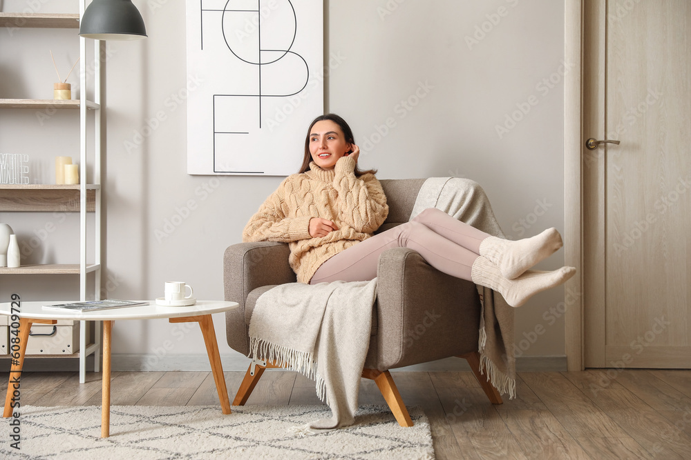 Young woman sitting in soft armchair at home