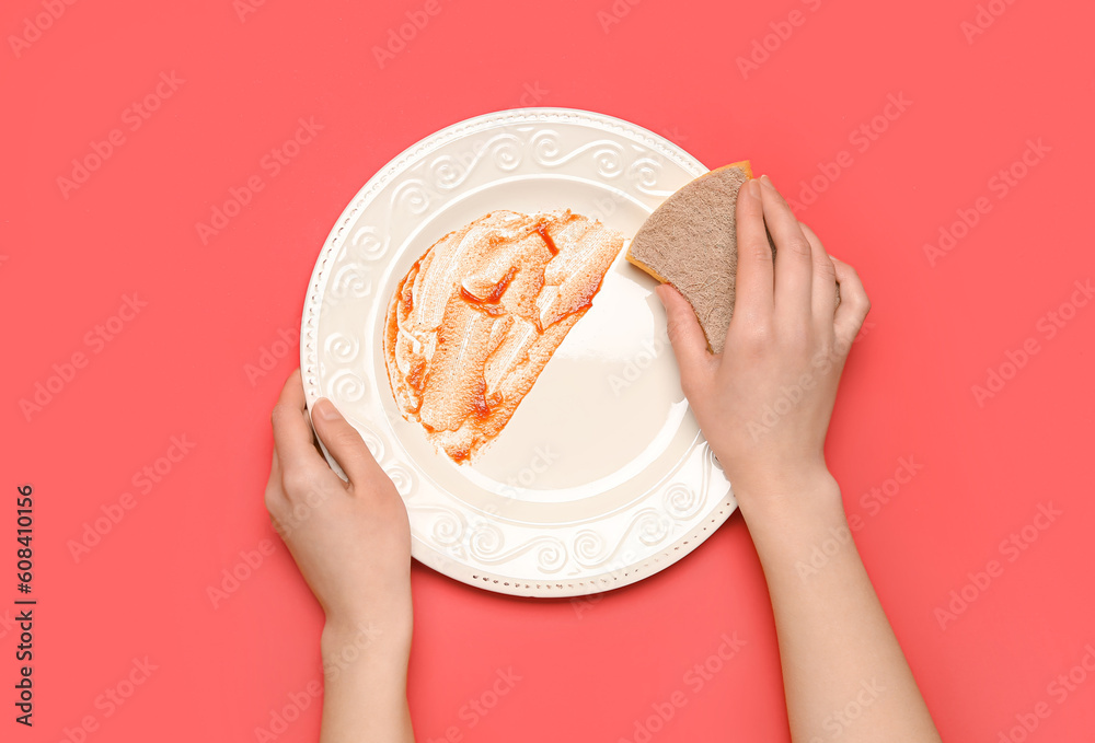 Woman washing dirty plate on red background