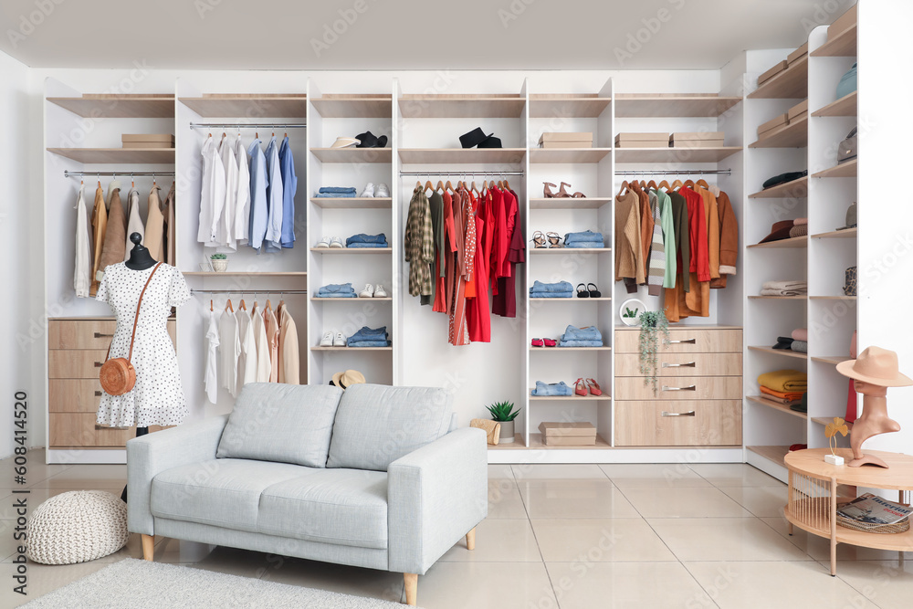 Interior of boutique with stylish clothes, mannequin and sofa